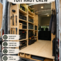 Intérieur aménagé d'un Ford Transit avec un lit escamotable et des rangements pratiques.